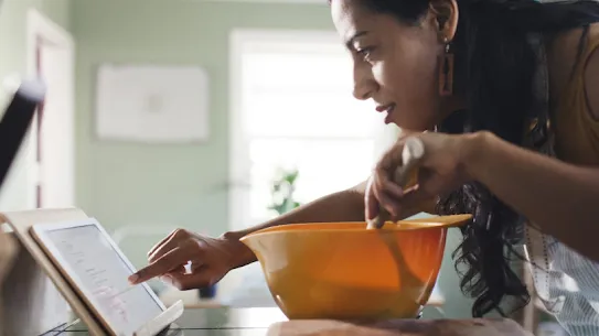 A woman uses her tablet to look up information while cooking