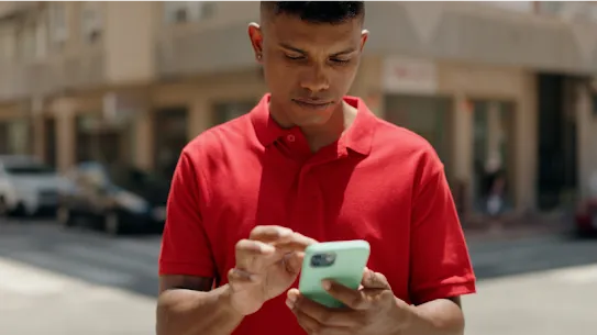 A young man looks intently at his smartphone screen